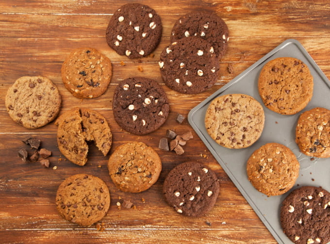 Pães de queijo com geleia sob uma tábua de madeira e uma caneca com café